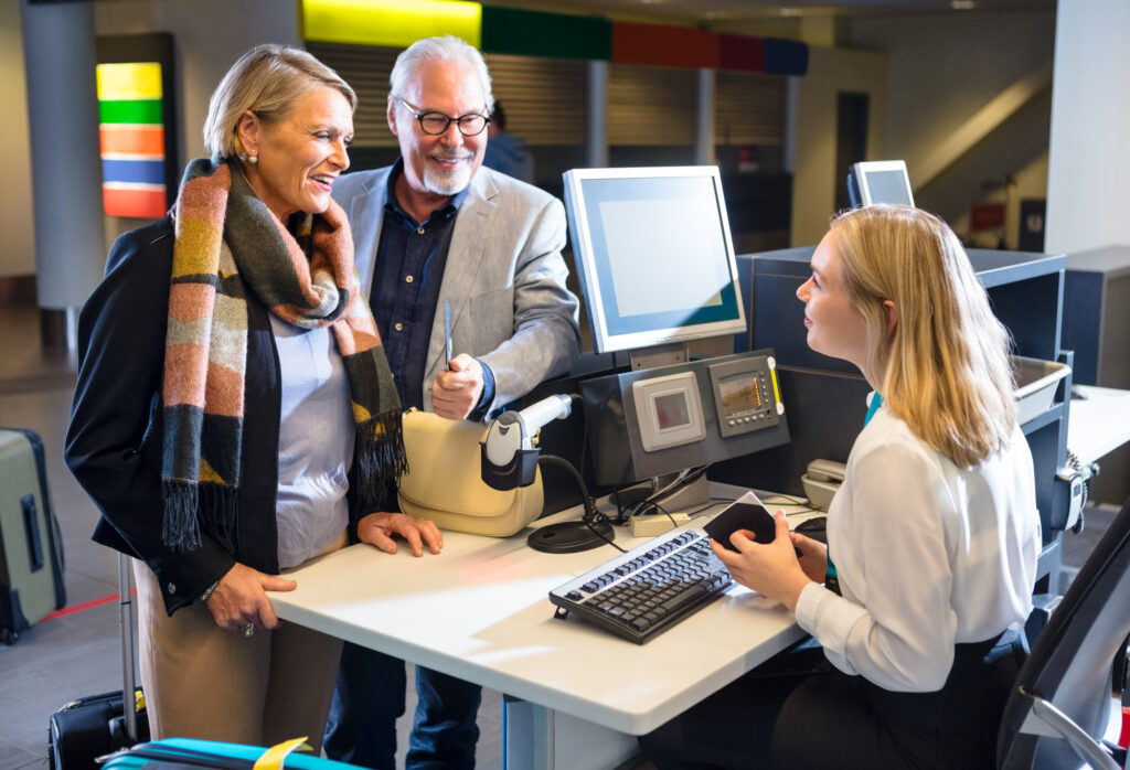 Business Couple Looking At Staff Holding Passport At Airport Check in