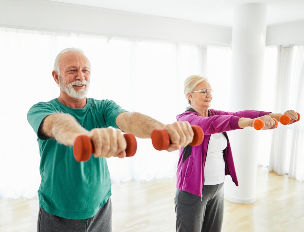 Two senior citizens - a man and a woman - exercise with weights.