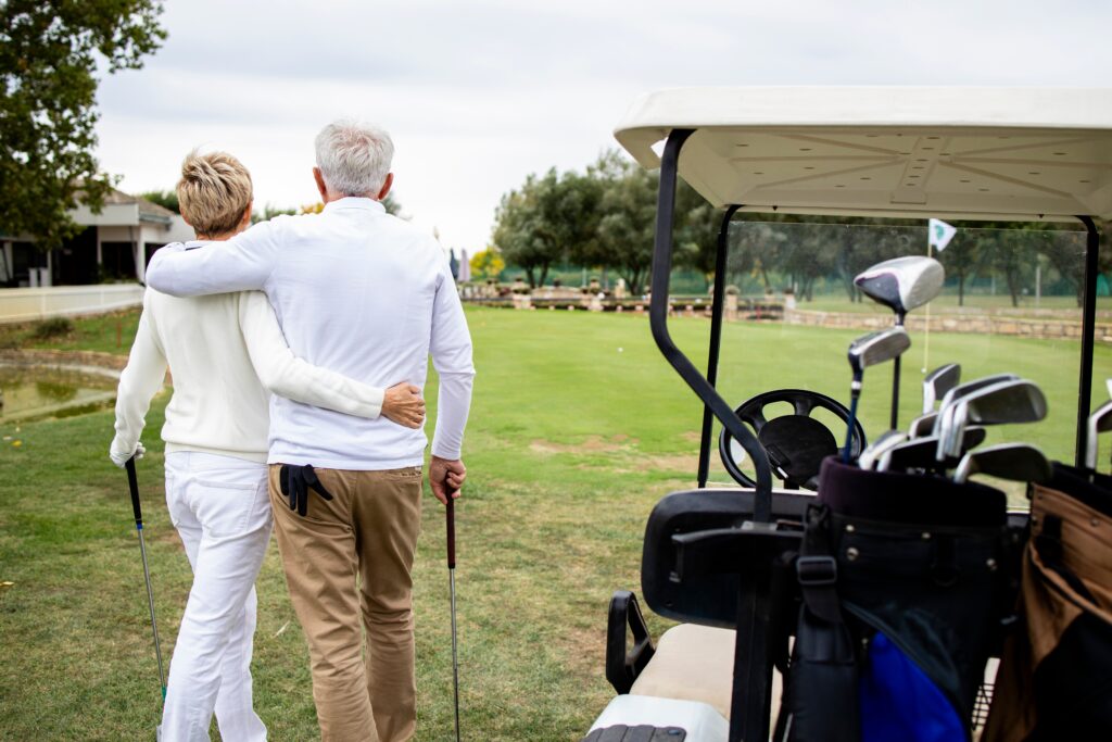 A retires couple embraces casually at a golf course.